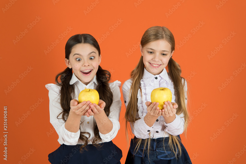 Growing in health. School children with healthy apple snack. Little girls taking school snack. Small girls eating natural vitamin food. Cute schoolgirls holding apples. Fruits are high in vitamin