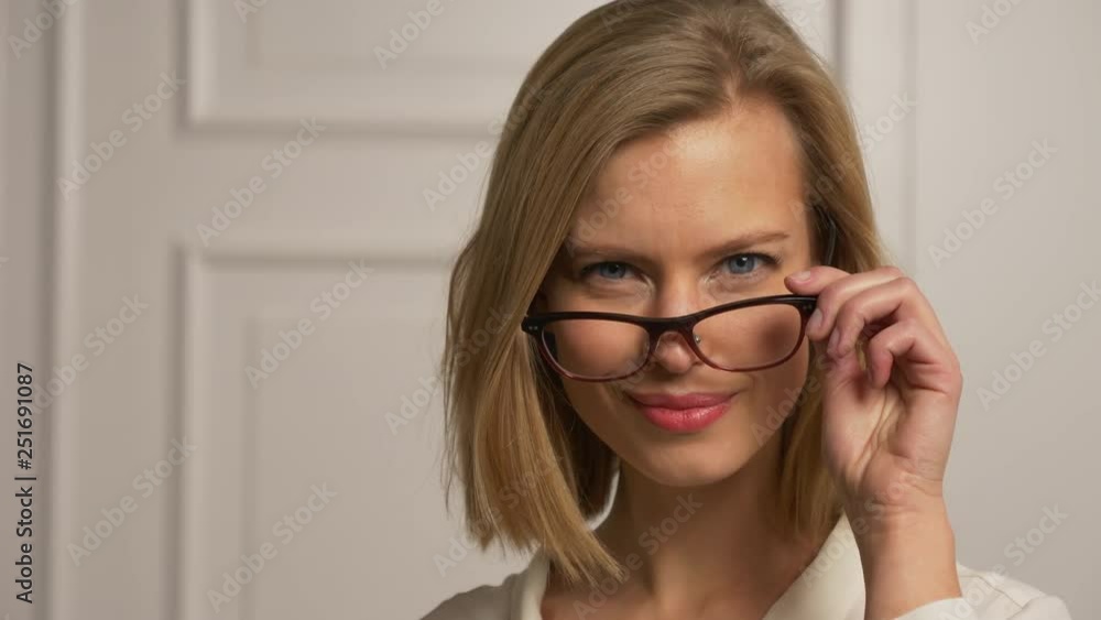 Model removes glasses halway and smiles Model removes glasses halway and smiles