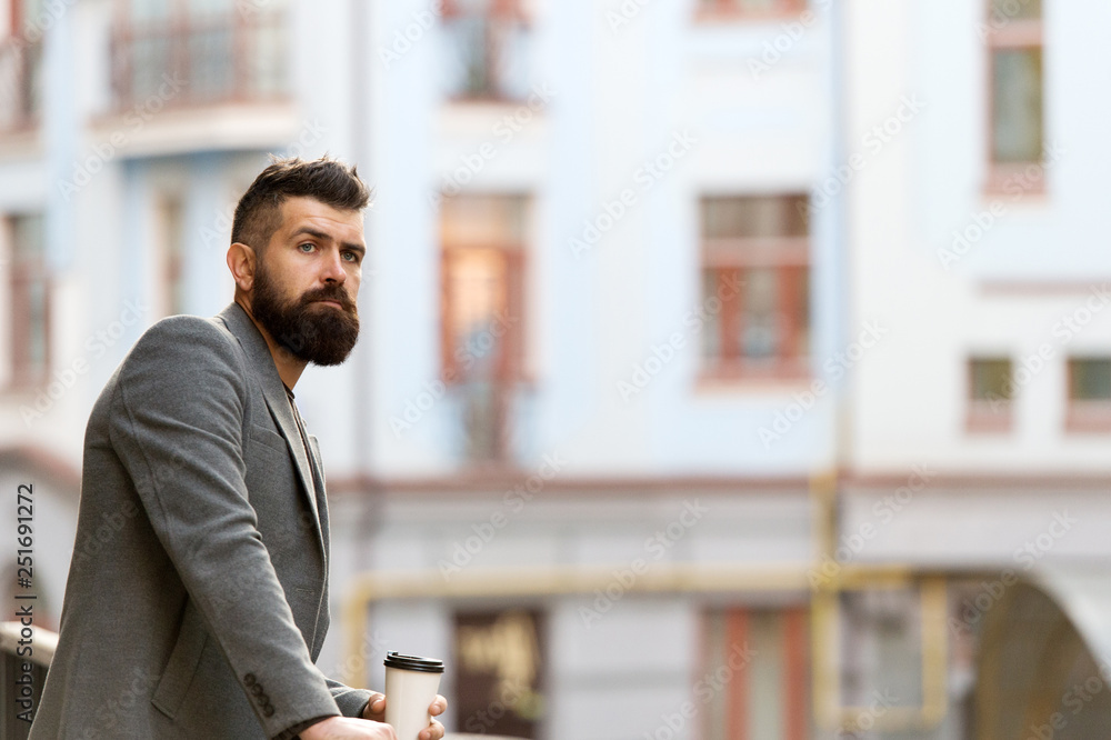 Early in the morning. Hipster with paper cup walking in city. Bearded man enjoying morning coffee. Businessman in hipster style holding takeaway coffee. The best time of day to drink coffee Early in the morning. Hipster with paper cup walking in city. Bearded man enjoying morning coffee. Businessman in hipster style holding takeaway coffee. The best time of day to drink coffee