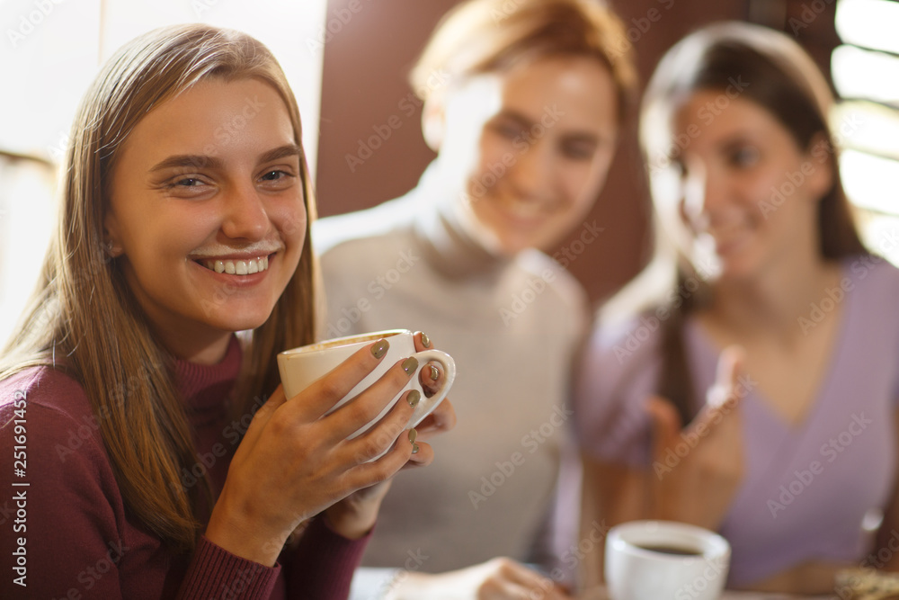 Young girl with coffee foam over upper lip smiling and looking at camera. Young girl with coffee foam over upper lip smiling and looking at camera.