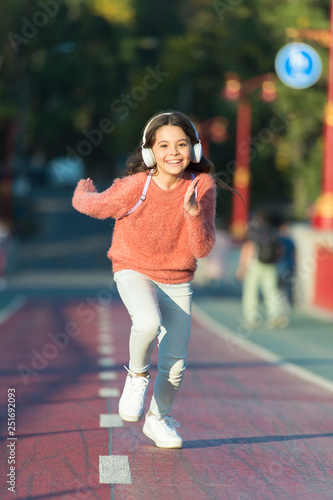 Girl cute with headphones. Little child enjoy activity. Kid walking running in park listening music. Music fills me with energy. Enjoy walk with favorite music in headphones. Playlist for active day