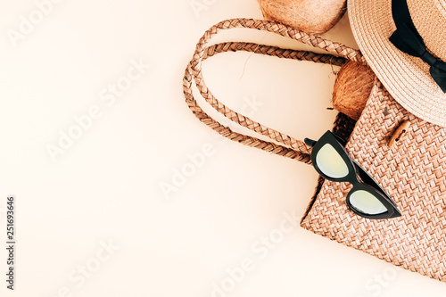 Summer concept. Straw bag, glasses, hat, coconut on pastel beige background. Flat lay, top view, copy space