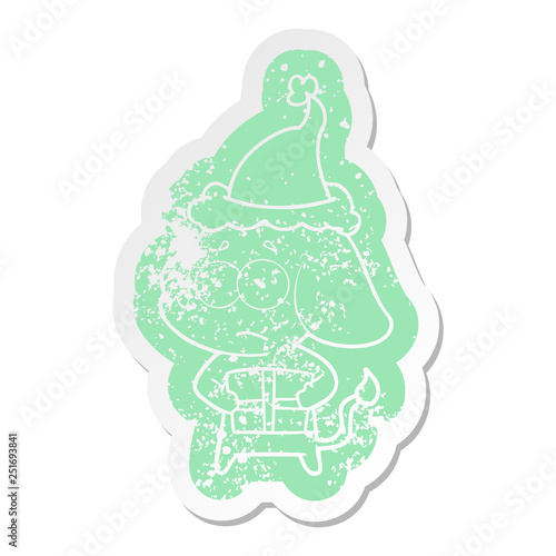 cartoon distressed sticker of a unsure elephant with christmas present wearing santa hat