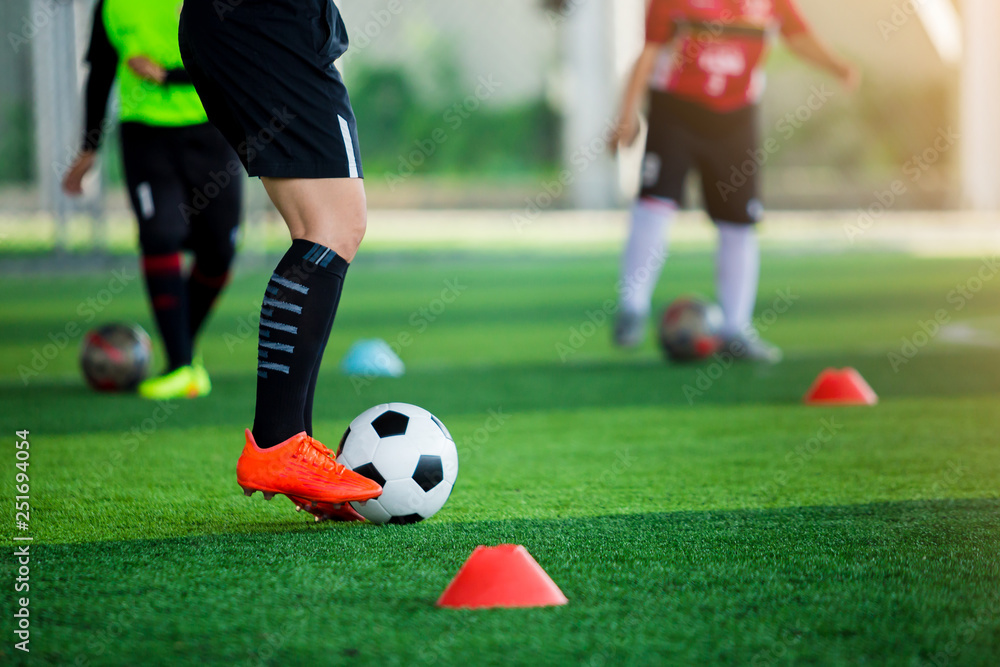 coach of soccer player standing and  stepping on the ball with blurry of young boy soccer player training.