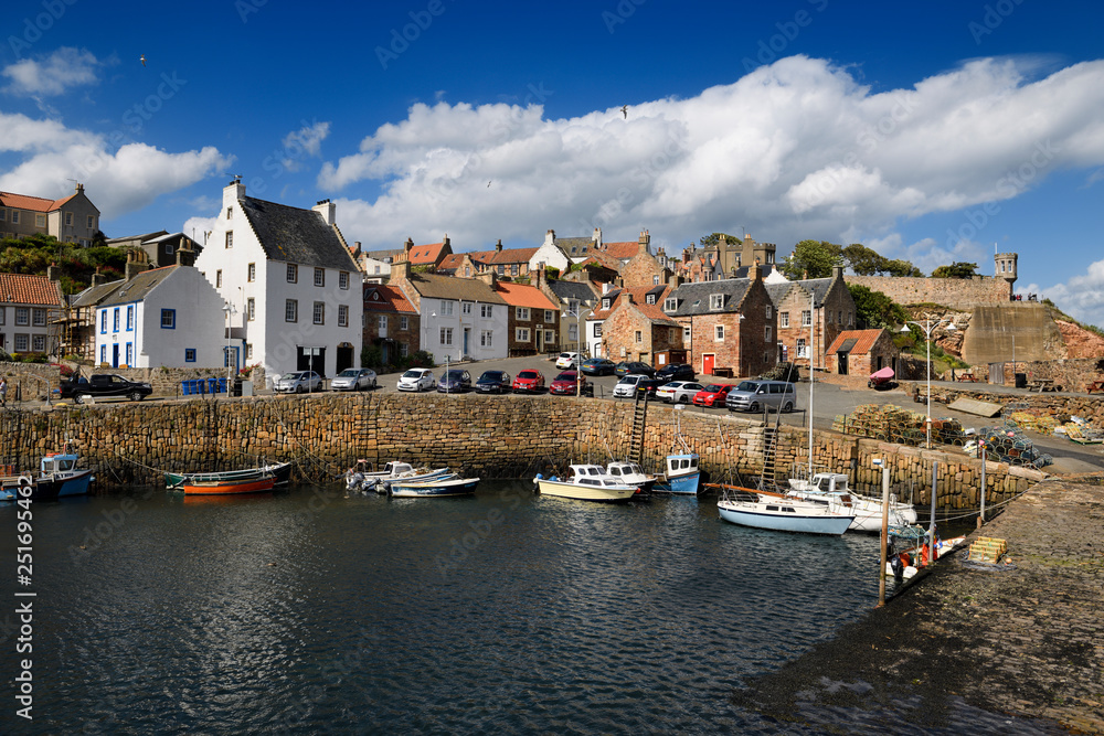 Stone ramp and pier walls at Crail Harbour with fishing boats and lobster traps in Crail Fife Scotland UK