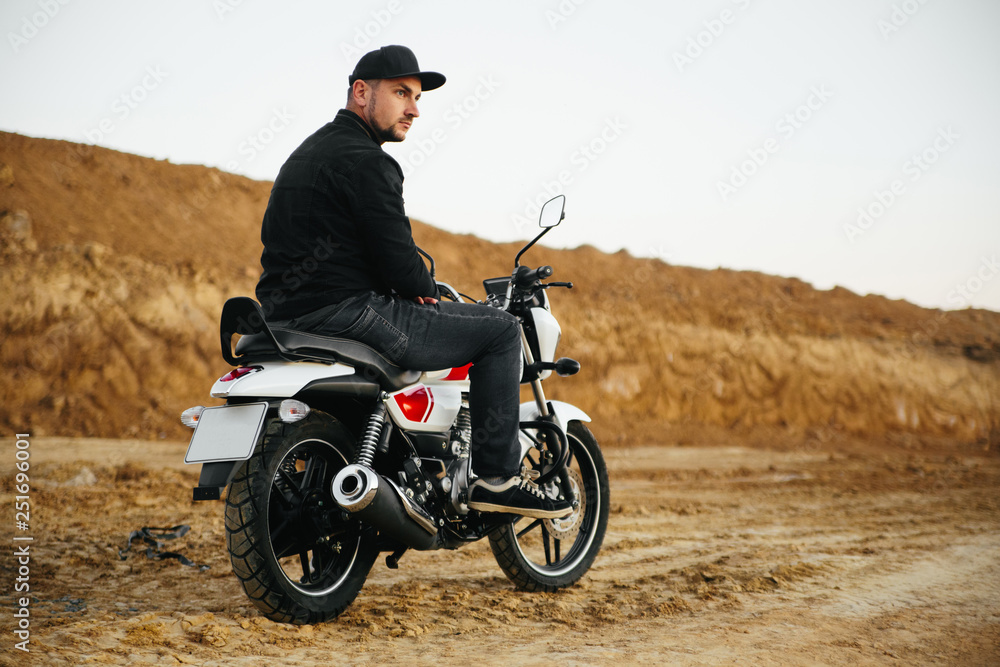 Fototapeta premium Smiling happy biker in sitting on motorcycle on road