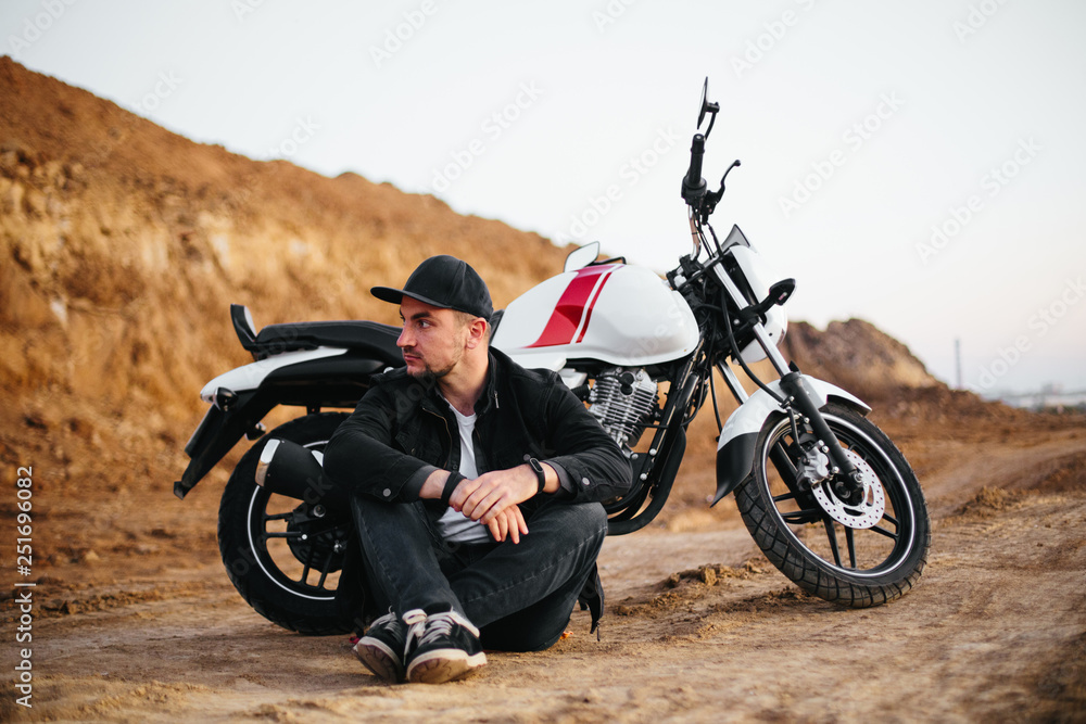 Fototapeta premium Smiling happy biker in sitting on motorcycle on road