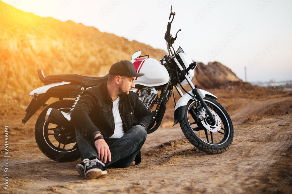 Obraz premium Smiling happy biker in sitting on motorcycle on road