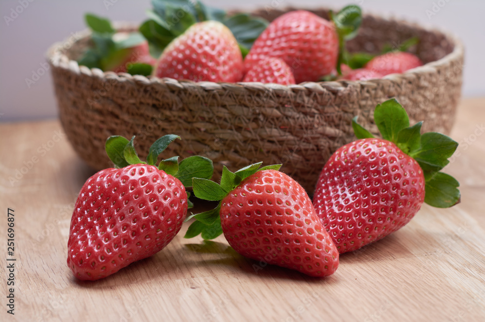 close up fresh strawberries with natural wood background in a basket