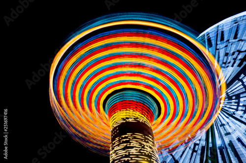 carousel and ferris wheel in an amusement park at night, long exposure. Concept of speed. photo