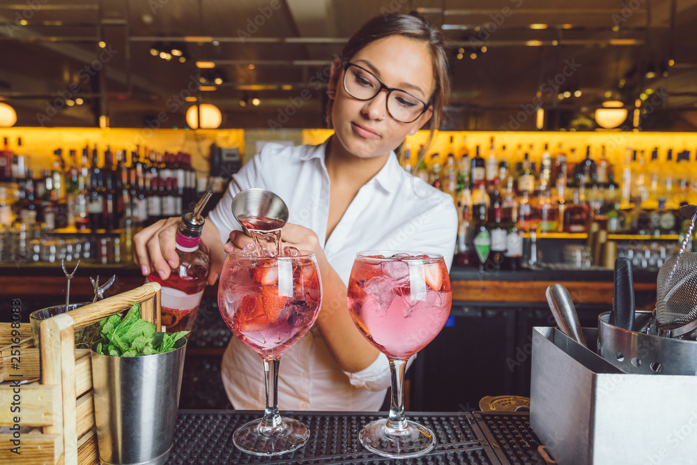 female beautiful smart bartender mixologist bar person makes prepares gin tonic cocktail drink pink mint fish bowl glass