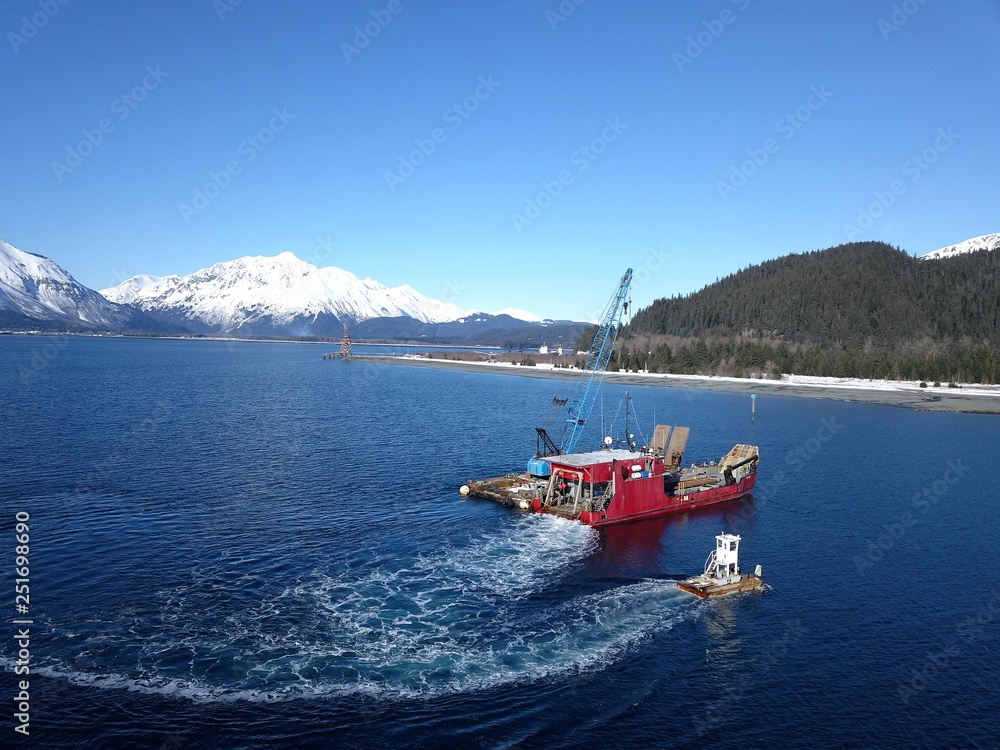 Obraz premium Work boats working together on Alaskan water to bring landing craft and barge into harbor