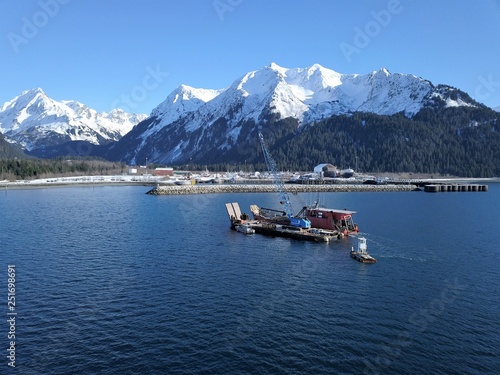 Work boats working together on Alaskan water to bring landing craft and barge into harbor