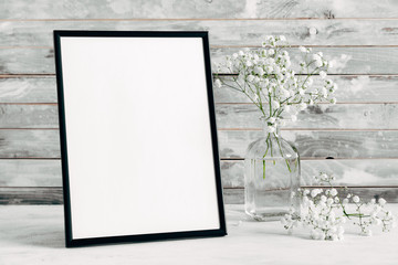 Blank photo frame and gypsophila flowers on wooden rustic wall background. copy space