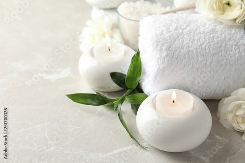 Beautiful spa composition with candles and flowers on marble background, space for text