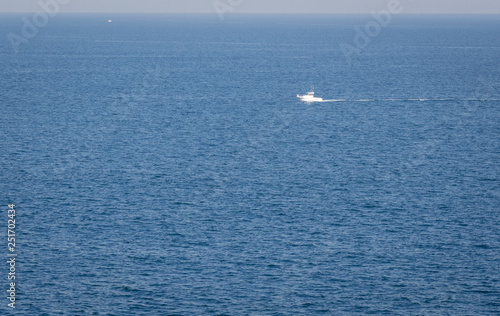 Minimal view of the Cantabrian sea Morning seascape with a lonely boat floating in the middle of the sea © Demianastur