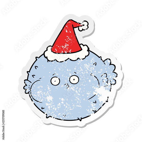 distressed sticker cartoon of a puffer fish wearing santa hat