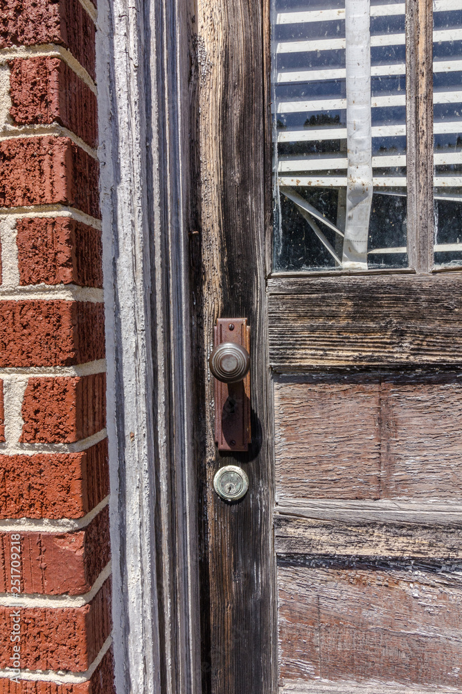 Closeup of abandoned wood door of red brick building with torn blinds Closeup of abandoned wood door of red brick building with torn blinds