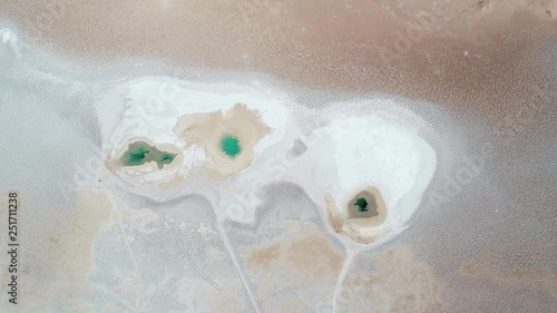 Senital aerial drone scene of blue lagoons at wide white salar. Camera turning general abstract nature image of sea eyes, natural drawings. Ojos de mar at Arizaro salar