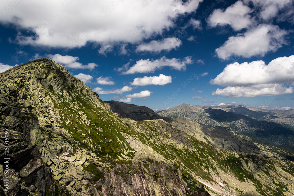 Fototapeta premium Rocks under blue sky with clouds. View of mountain valley. Tourism, travel to mountains.