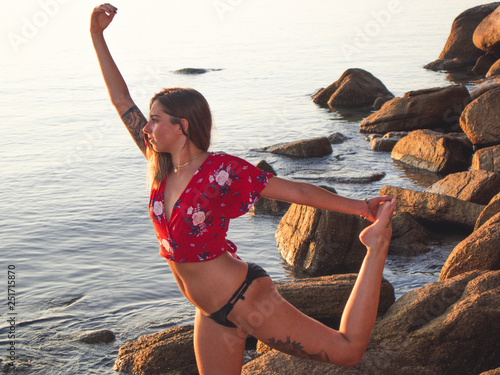 Silhouette Young Woman Practicing Yoga On The Beach At Sunset photo