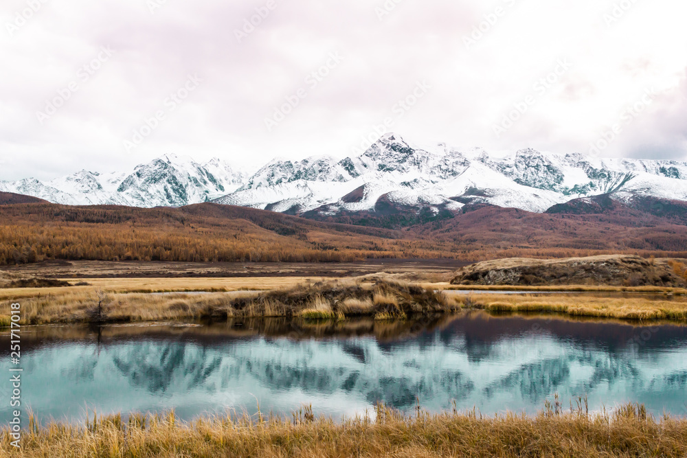 Autumn panorama. View of mountains and lake. Mountain range on horizon. Travel to mountain valley with rivers.