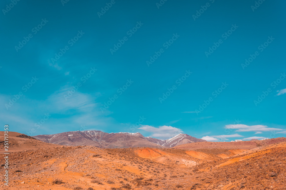 Naklejka premium Yellow and red rocks under blue sky. Desert landscape with mountains.
