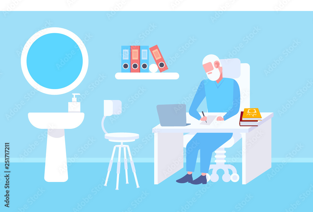 senior doctor sitting at table workplace using laptop and writing prescription modern clinic office interior medicine and healthcare concept full length flat horizontal