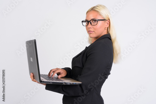 Young blonde businesswoman thinking while using laptop