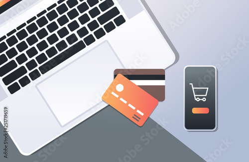 online shopping mobile application internet payment concept top angle view desktop smartphone laptop screen credit card office stuff horizontal