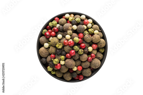 Mixture of peppers hot, red, black, white and green pepper in clay bowl isolated on white background. Seasoning or spice top view