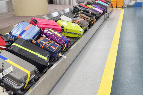 Bright green, pink and blue suitcases on luggage conveyor belt