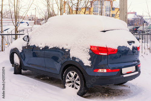 Blue car in the winter in the parking lot. The car was covered with snow, little snow, big drifts, cold, winter.