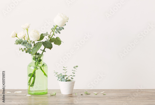 eucalyptus twigs and roses  in  glass vase on white background