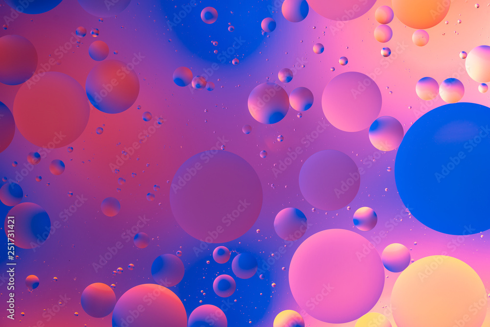 purple and orange oily drops in water with colorful background, close-up purple and orange oily drops in water with colorful background, close-up
