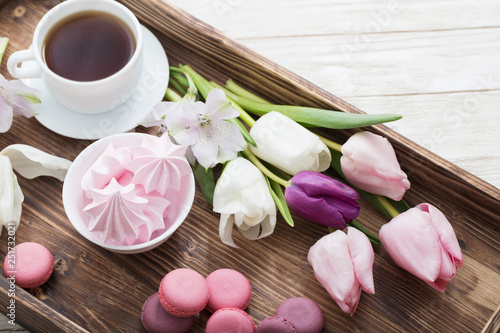 Tulips and cup of coffee with dessert on white background. Conce