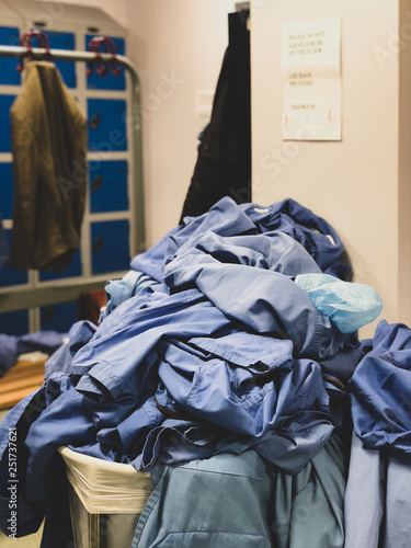 A clothes basket overflowing with surgical scrubs in the changing room of a hospital in the United Kingdom - untidy environment of the locker room. 