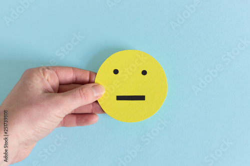 Fotografie Crop hand with yellow indifferent smiley
