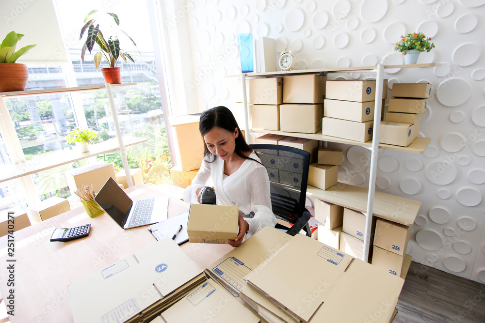 Young asian girl is freelancer Start up small business owner writing address on cardboard box at workplace,Shipping shopping online small business entrepreneur SME or freelance Young asian girl is freelancer Start up small business owner writing address on cardboard box at workplace,Shipping shopping online small business entrepreneur SME or freelance