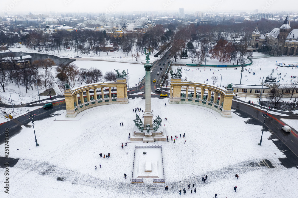 Obraz premium Budapest, Hungary - Snowy Heroes' Square and Millennium Monument from above on a cold winter day with City Park (Varosliget), Szechenyi Thermal Bath, Vajdahunyad Castle and ice rink at background