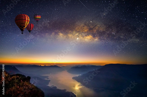 Milky way and balloons before sunrise on view point with long exposure photograph, with grain at Pha daeng Luang Viewpoint, Mae Ping Nation Park, Lumphun, Thailand.
