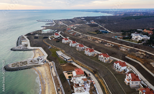 Panoramic aerial view of the cottage settlement by sea. Top view of the marine cottage village, line of strengthening the coast in zone of landslide. Villa on the sea panoramic view from height