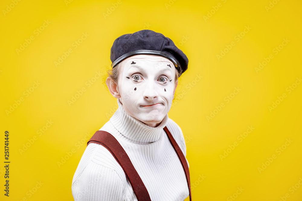 Portrait of an actor as a pantomime with white facial makeup showing expressive emotions on the yellow background indoors Portrait of an actor as a pantomime with white facial makeup showing expressive emotions on the yellow background indoors