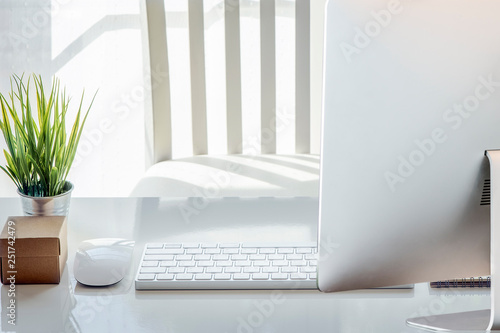 mouse, blank note, pencil, white keyboard,eyeglasses and houseplant on white table © NAMPIX