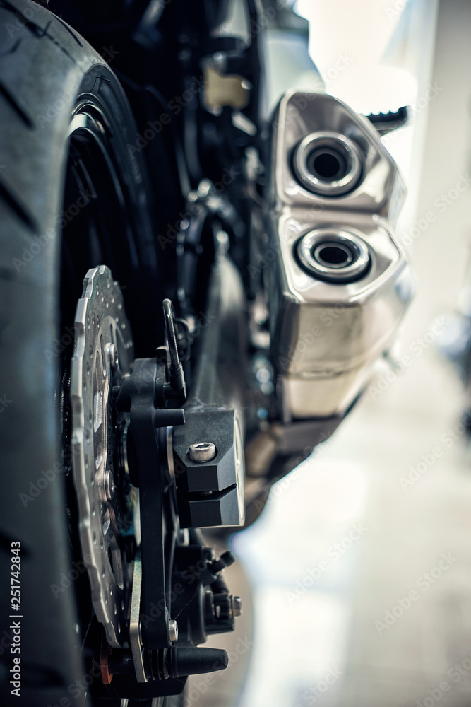 View of the back of a motorcycle with an emphasis on the chain. View of the back of a motorcycle with an emphasis on the chain.