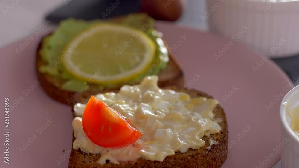 Placing a tomato on a toast with eggs salad Placing a tomato on a toast with eggs salad