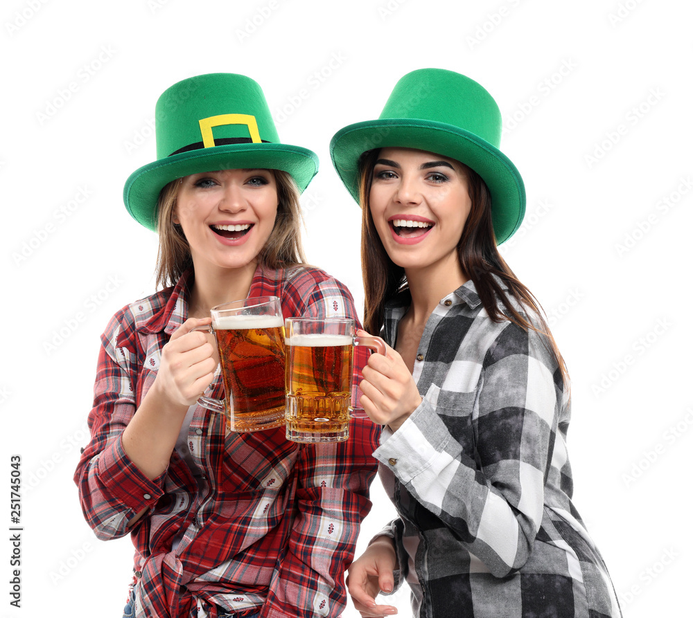 Beautiful young women with green hats and mugs of beer on white background. St. Patrick's Day celebration Beautiful young women with green hats and mugs of beer on white background. St. Patrick's Day celebration