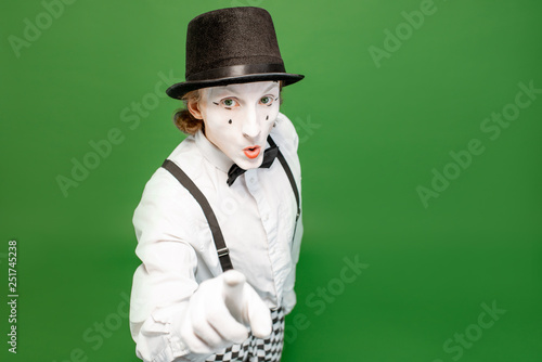 Portrait of an actor as a pantomime with white facial makeup posing with expressive emotions isolated on the green background