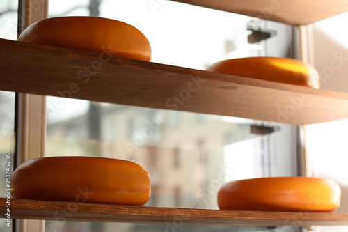 Tasty cheese on shelves in ...