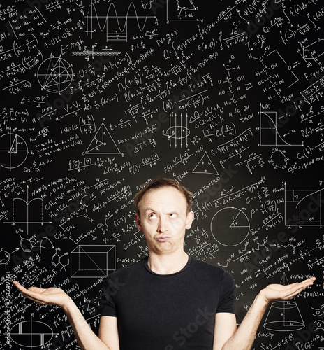 Casual man with empty open hands on blackboard science background. Education, student exam and brainstorm concept